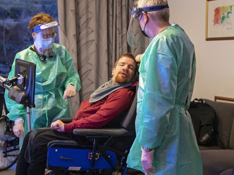Starfsfólk sinnir íbúa í sóttkví í fullum skrúða. 