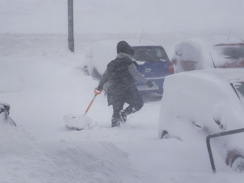 Kona að brjótast í gegnum skafl með skóflu í hendi.