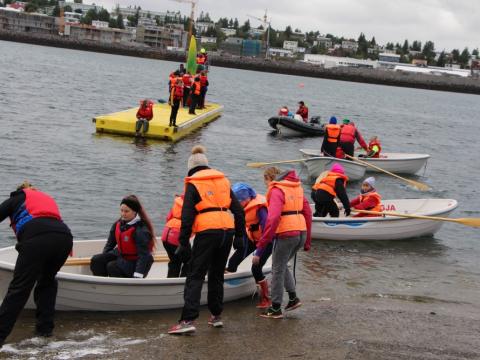 Börn og fullorðnir í Siglunesi við Nauthólsvík á árabátum og á "stökkpalli" fyrir báta.
