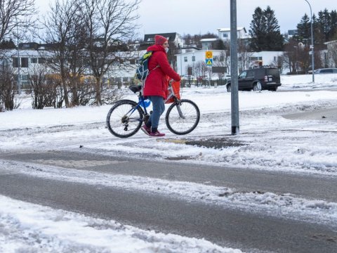 Kona á reiðhjóli á gatnamótum.