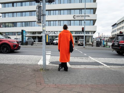 A pedestrian waits at a traffic light near Hlemmur.