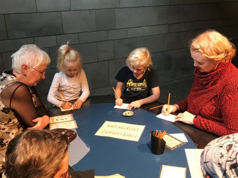 Börn og fullorðin leysa rúnaþraut.