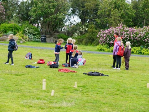 Börn spila kubb á túni í sumarfrístund.