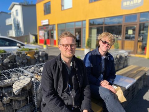 Two men sit on a bench outside Brauð &amp; Co at Laugalækur.