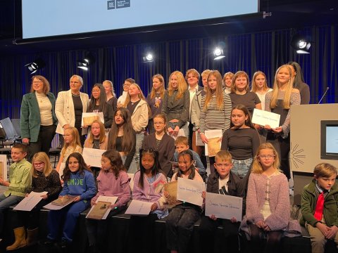 Hópur barna sem hlaut Íslenskuverðlaun unga fólksins 2023. Hópmynd á sviði í Hörpu.