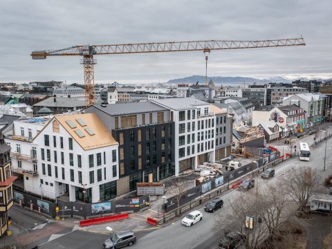 Hús, byggingarkrani, gata og bílar.