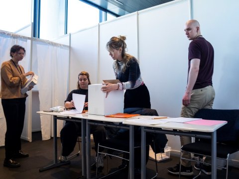 Four people staff a polling station in City Hall.