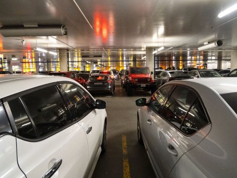 In the Harpa parking garage. View between two cars in the foreground, with more cars visible in the background.