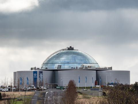Perlan and the geothermal water tanks beneath it. Winter or spring, gray sky.