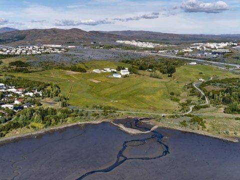 Aerial photo showing Keldur area, sea, grass, trees, buildings.