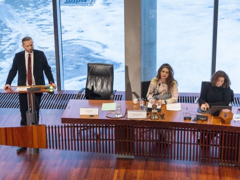 Mayor Einar Þorsteinsson stands at the podium in the City Council chamber. Magnea Gná and Helga Laxdal are seated at a table