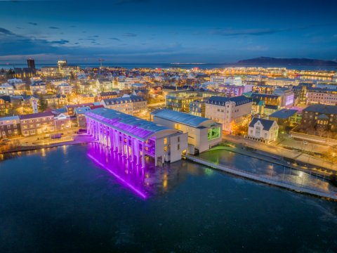 Reykjavík City Hall in winter, aerial view, illuminated with purple lights. The Kvosin area is also visible from above.
