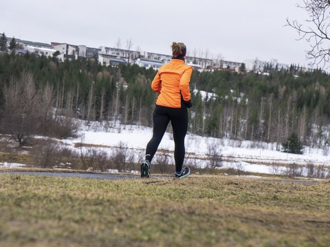 Kona að hlaupa úti. Skógur og snjór.