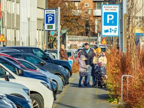 bílar við götu og fólk á gangstétt