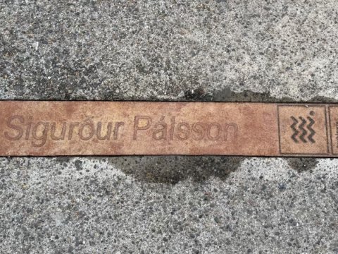 Bronze-colored sign in sidewalk with the name of author Sigurður Pálsson. Part of the literary installation at the Customs House.