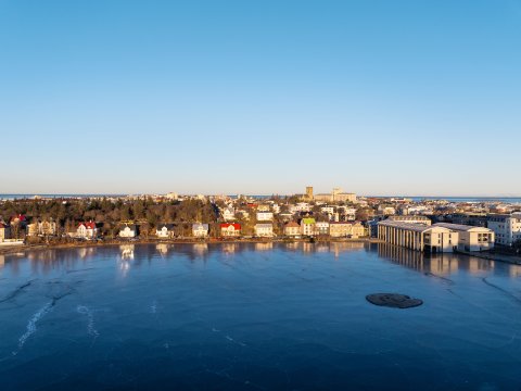 Tjörnin, Tjarnargatan, séð frá Þingholtum, loftmynd. Blá Tjörn í forgrunni, blár himinn í bakgrunni. Logn, heiður himinn.