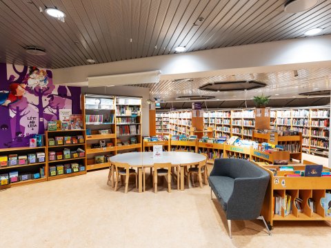The Reykjavík City Library at Kringlan. A wide interior shot of the library features a central round table and walls lined with bookshelves. This is likely the children's section.