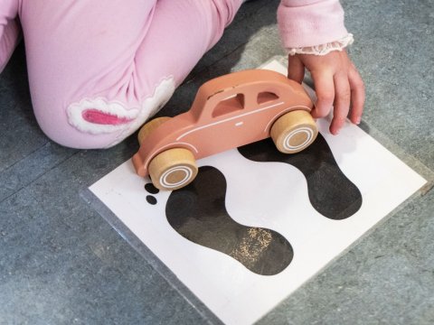 A child is seen playing with a toy car.