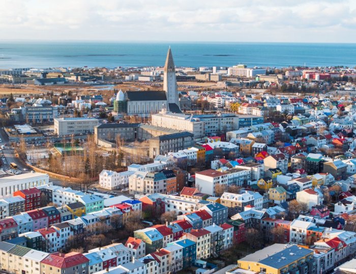 Aerial view of the city center, with Hallgrímskirkja church in the center, airport and ocean in the background. Sun.