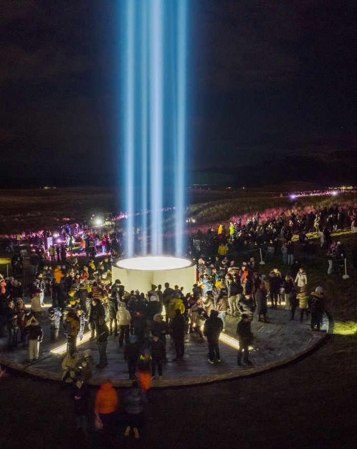 Lighting of the Imagine Peace Tower in Viðey. A crowd gathers at the tower after dark.