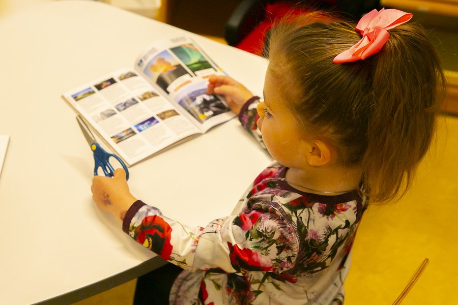 Girl cutting pictures from a pamphlet at Bakkaborg.