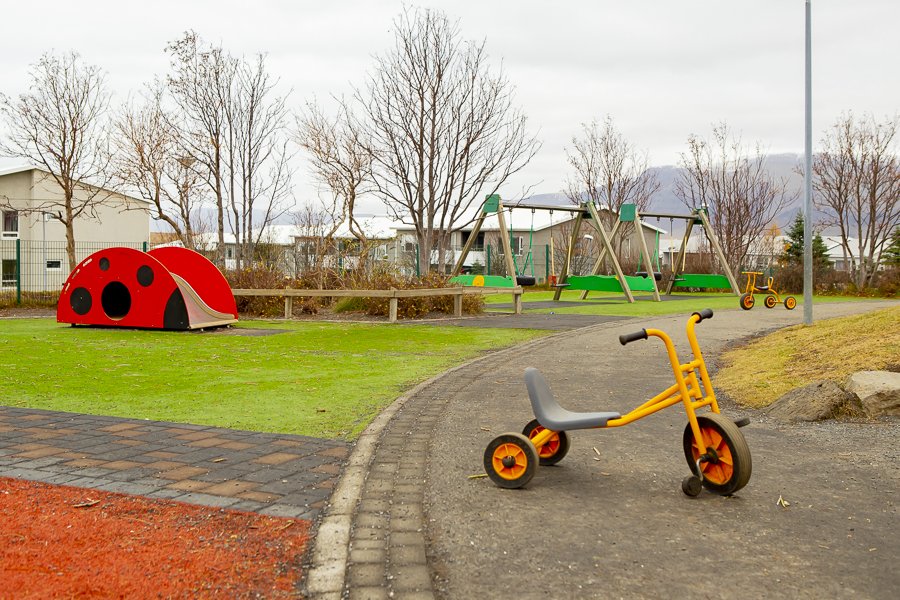 Playground equipment and tricycle in Nes preschool's outdoor area at Hamravík