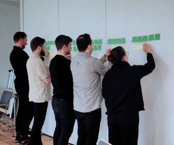 People sticking post-it notes with ideas on a wall.