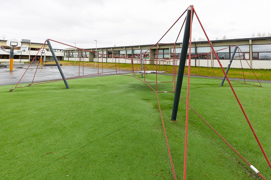 Large jungle gym with red rope standing on artificial grass. 