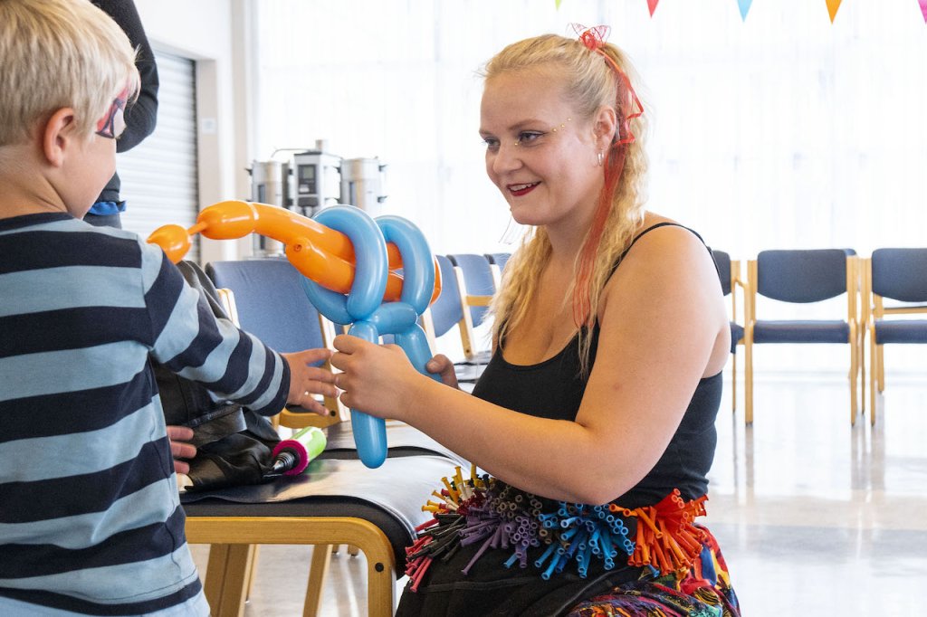 Blöðrulistakona býr til blöðrulistaverk handa barni. 