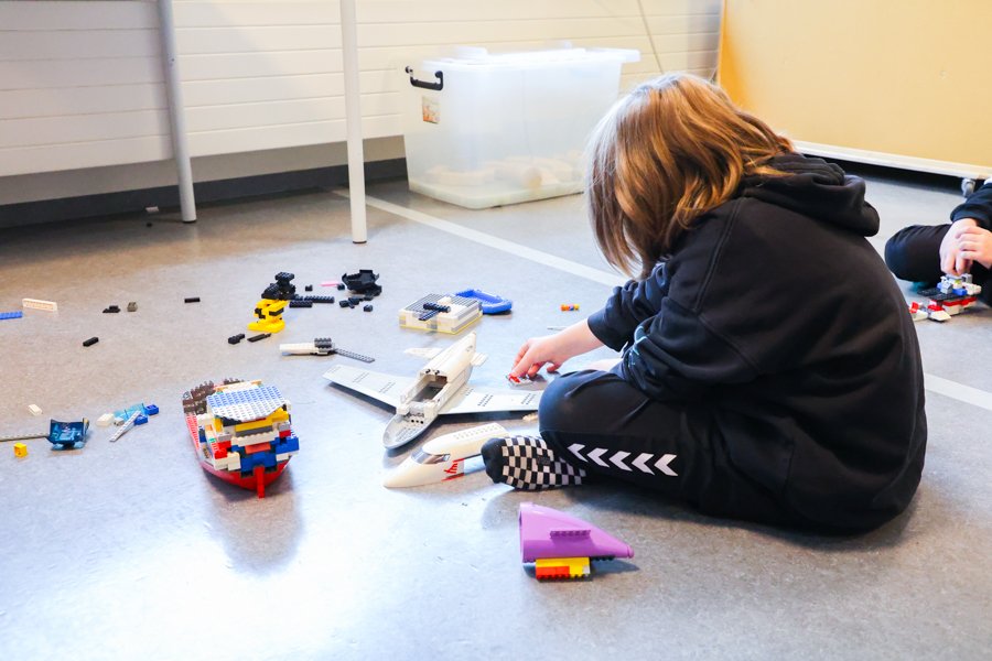 A child sits on the floor with Lego blocks.