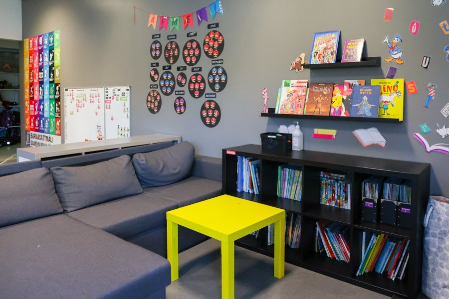 A sofa, small coffee table and low shelf with books. Wall shelves above with books and decorations on the wall.