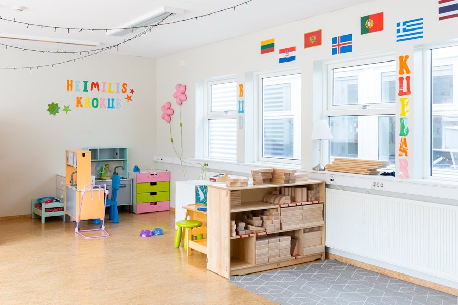 A cozy corner for children, a shelf with large wooden blocks and flags on the wall.