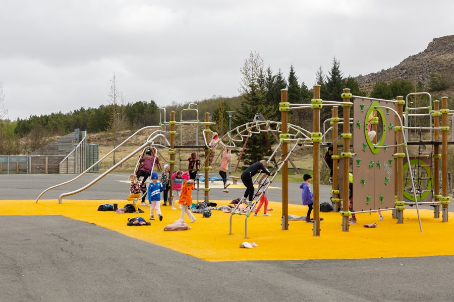 A jungle gym on a yellow surface, with children playing. 