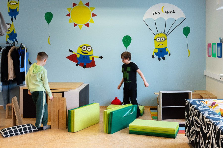 Room at the Frostheimar after-school program with decorated walls, cushions and two children playing.