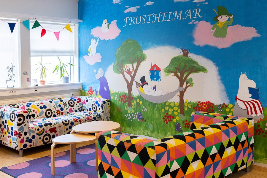 Room at the Frostheimar after-school program with wall decorations featuring Moomin characters. Decorative sofas and tables in front.