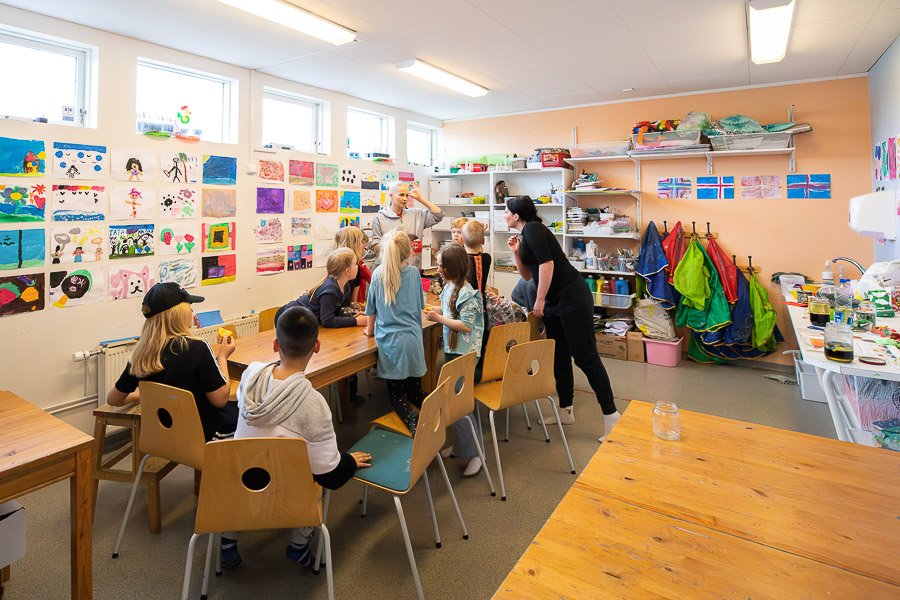 Children listen to an instructor while seated at a table at the Glaðheimar after-school program