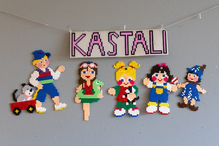 The word kastali made of beads and hung on the wall along with beaded figures. 