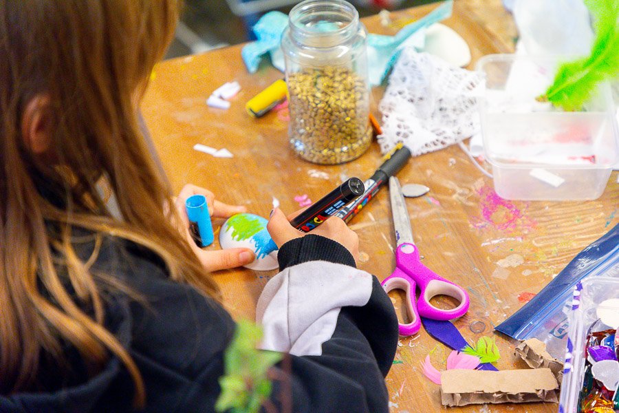 A child sits at a table doing crafts.