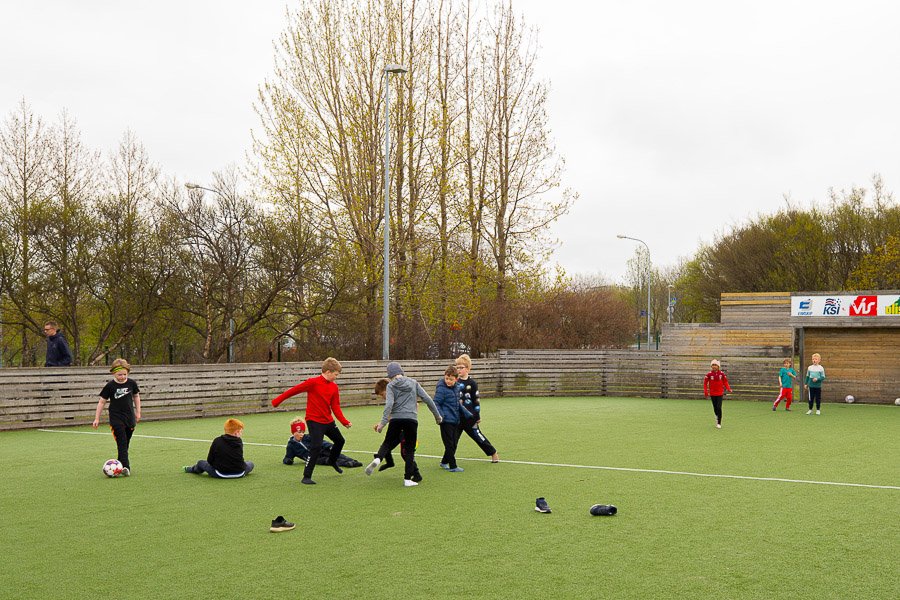 Children playing soccer on grass field at Laugarsel after-school program.