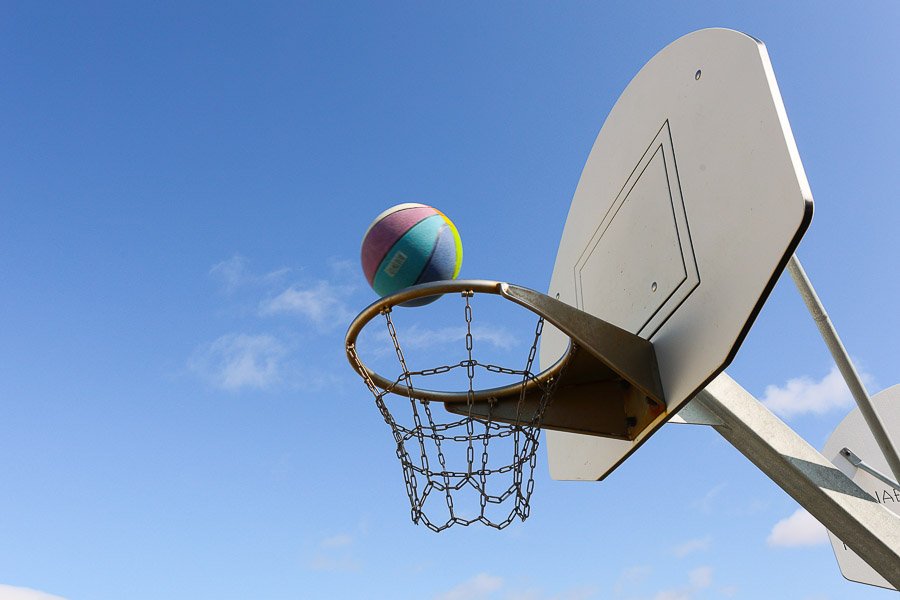 Basketball hoop and ball that's about to go into the basket.