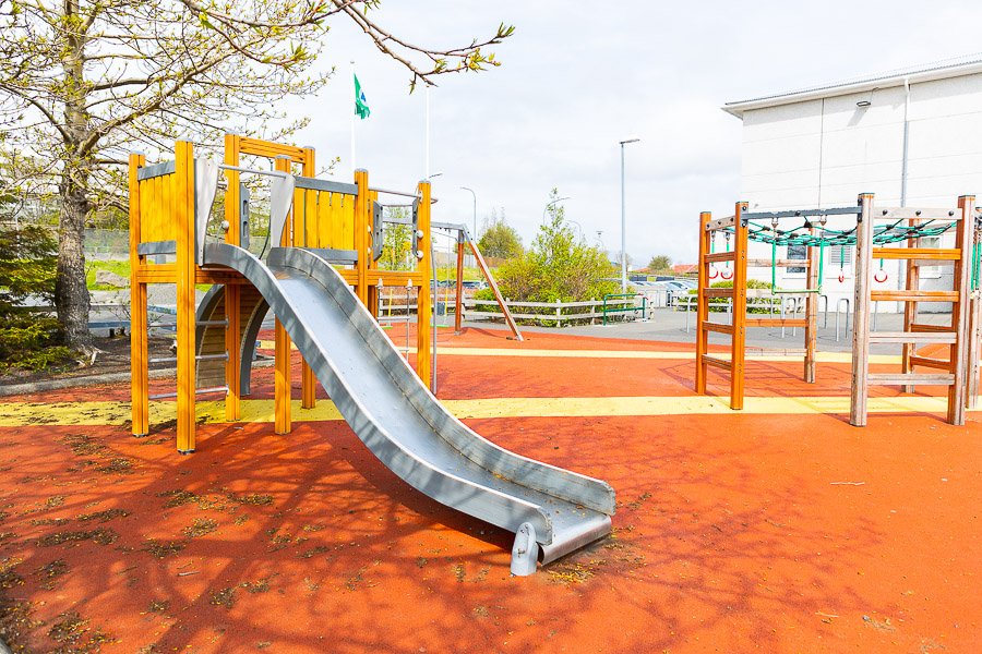 A slide and a jungle gym on a red surface.