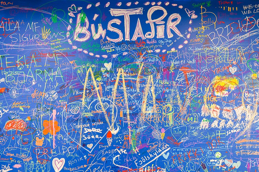 Large blue board with various artwork and the heading Bústaðir
