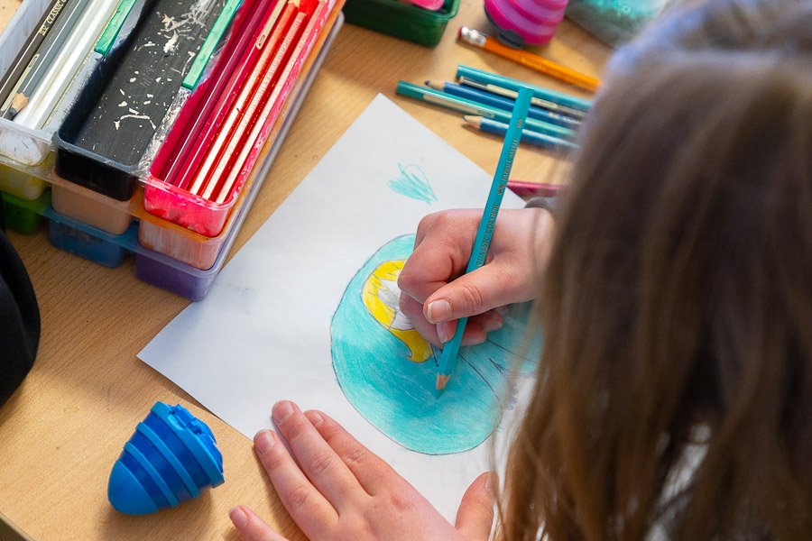 A child sits at a table drawing and coloring.
