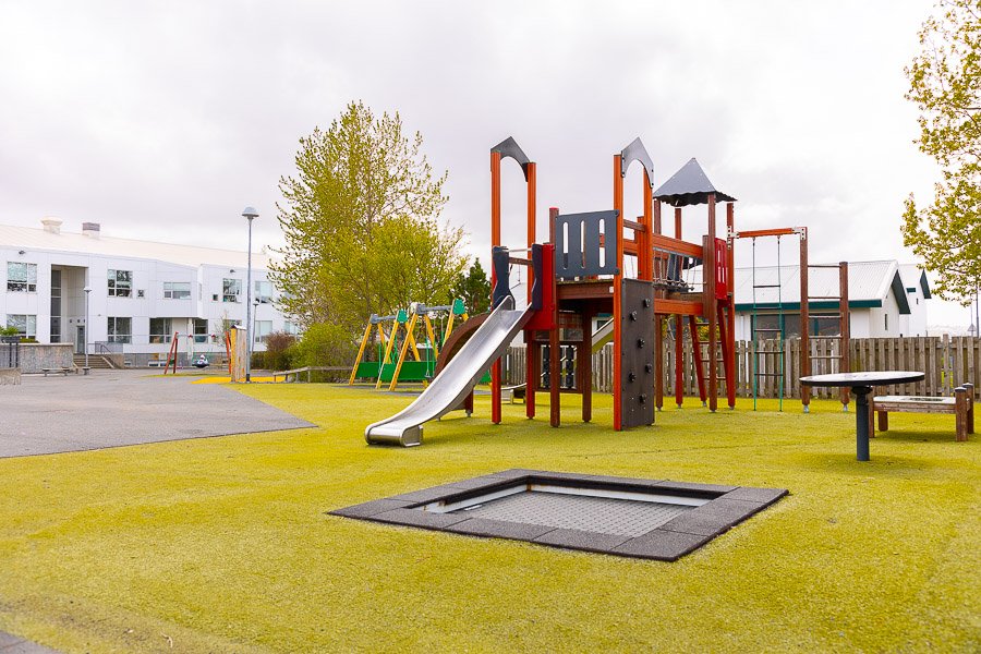 A playground with a castle, a slide, and a trampoline.