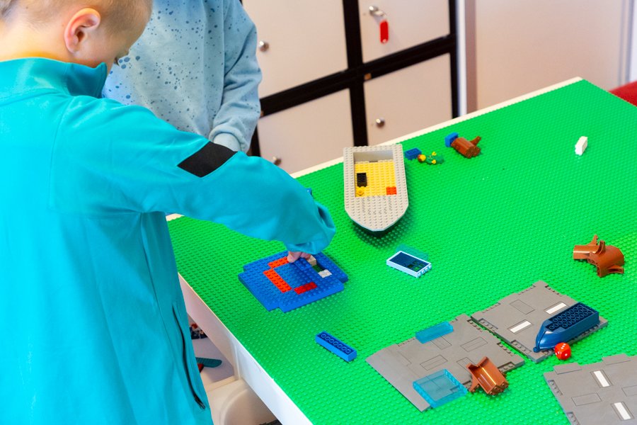 A child building with Lego blocks on a table.