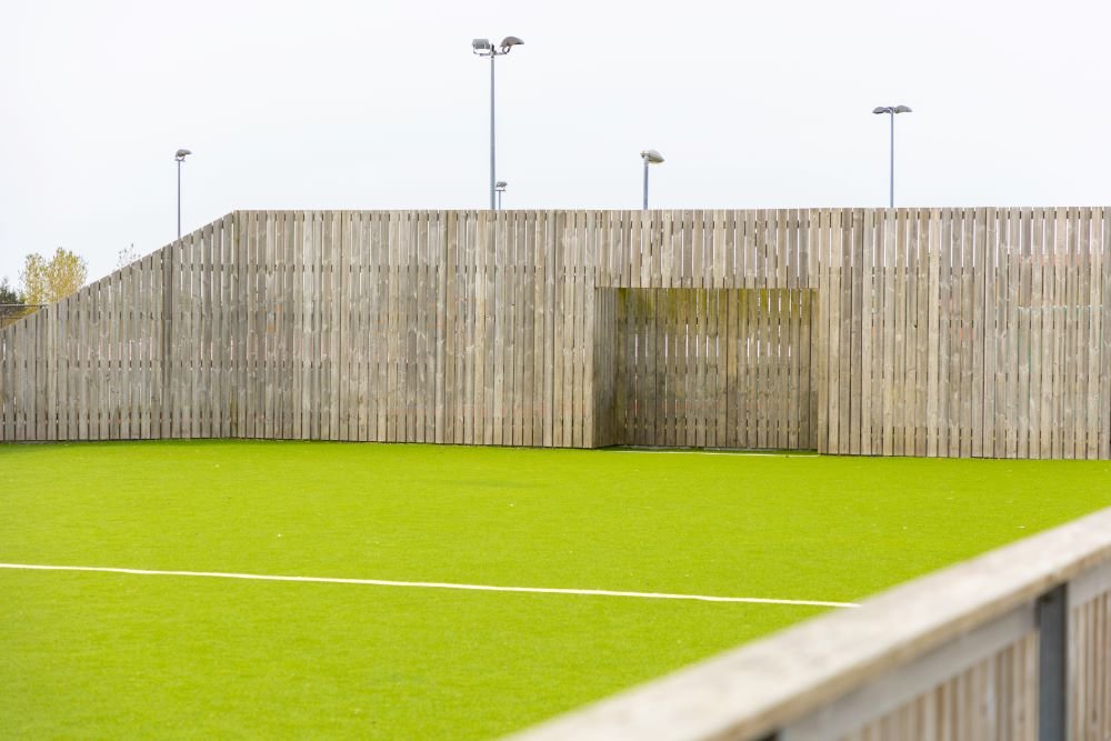 An outdoor soccer field surrounded by fencing. 