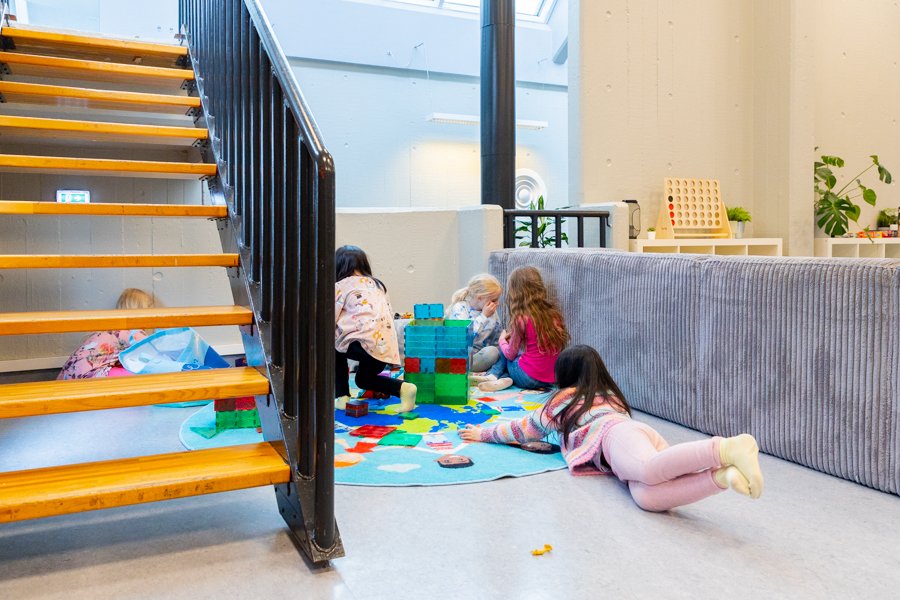 A group of children playing on the floor with clear blocks. Stairs to the side. 