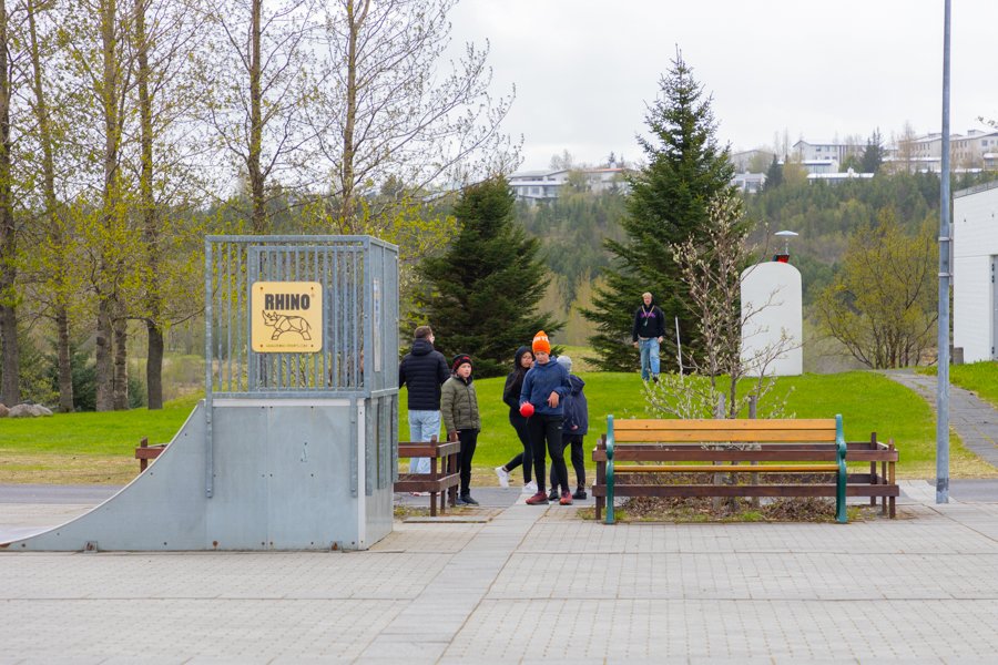 Children on an outdoor playground. A skateboard ramp and benches. 
