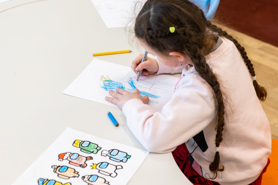 A child sits at a table drawing and coloring.
