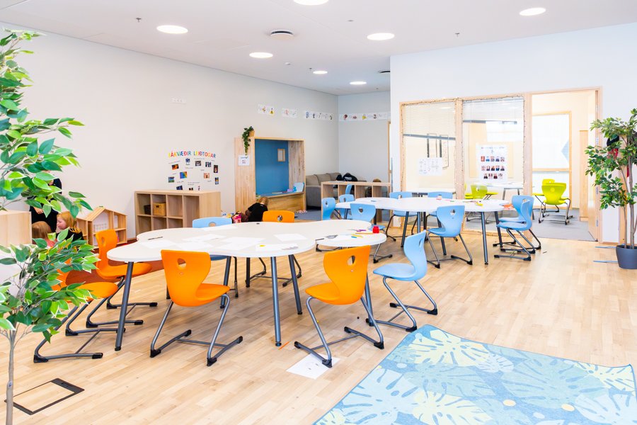A hall with tables, chairs and a rug on the floor. 